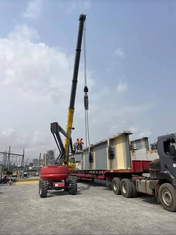 Grue mobile SLMG levant une poutre d'acier sur porte-char